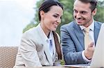 Happy businesspeople discussing over laptop outdoors