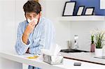 Young ill man blowing nose in tissue paper