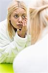 Young woman examining eye in mirror