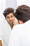 Reflection of ill man examining eyes in mirror