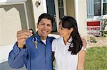 Young couple holding keys outside new home portrait