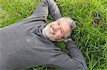 Mature man smiling laying on the grass