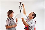 Father and son installing a ceiling lamp and fluorescent lightbulb together
