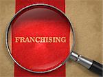 Franchising Concept. Magnifying Glass on Old Paper with Red Vertical Line Background.