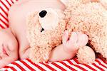 sleeping cute little baby on red and white stripes pillow with teddy bear