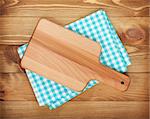 Cutting board over kitchen towel on wooden table background