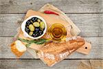 Italian food appetizer of olives, bread, olive oil and spices on wooden table background
