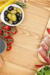 Red wine with olives, tomatoes, prosciutto, bread and spices. Over wooden table background. View from above with copy space