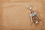 Corkscrew with red wine stains on brown paper background with copy space