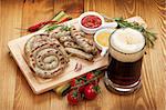 Grilled sausages with ketchup, mustard and mug of beer. Over wooden table background