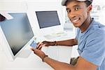 Portrait of a casual young man doing online shopping through computer and credit card in office