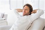 Relaxed well dressed man sitting with hands behind head on sofa in the house