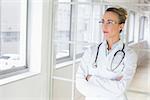 Beautiful serious young female doctor standing with arms crossed in the hospital