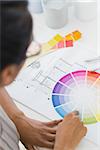 Interior designer looking at colour wheel at her desk in creative office