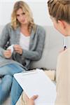 Therapist holding clipboard and listening to patient at therapy session