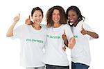 Happy team of volunteers giving thumbs up at camera on white background
