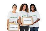 Team of volunteers smiling at camera holding donations boxes on white background