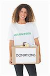 Smiling volunteer holding a box of donations on white background