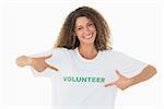 Smiling volunteer pointing to her tshirt looking at camera on white background