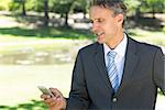 Mature businessman text messaging through cellphone in park