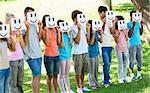 Group of multiethnic friends holding smileys in front of faces at park