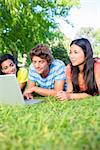 University students using laptop together while lying on college campus