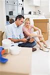 Couple using digital tablet amid boxes in a new house