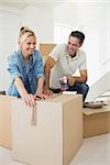 Portrait of a smiling couple packing boxes in a new house