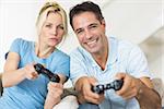 Portrait of a cheerful couple playing video games in the living room at home