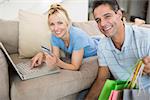 Portrait of a smiling couple doing online shopping through computer and credit card at home
