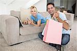 Portrait of a smiling couple doing online shopping through computer and credit card at home