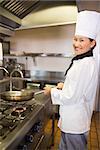 Side view portrait of a female cook preparing food in the kitchen