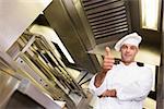 Portrait of a smiling male cook gesturing thumbs up in the kitchen