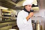 Side view of a male cook drinking red wine in the kitchen