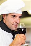 Closeup of a male chef smelling red wine in the kitchen