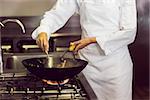 Mid section of a female chef preparing food in the kitchen