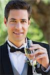 Closeup portrait of handsome groom drinking champagne in garden