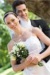 Portrait of loving groom embracing bride from behind in garden