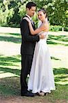 Full length of young newly wed couple embracing in garden