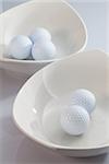 Two white ceramics bowls and golf balls