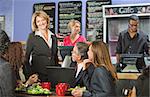 Smiling cafe owner with group of business people