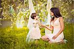 Happy woman and child in the blooming spring garden.Child kissing woman. Mothers day holiday concept