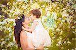 Happy woman and child in the blooming spring garden.Child kissing woman. Mothers day holiday concept