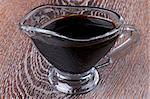 Soy Sauce in in Glass Gravy Boat isolated on Wooden background