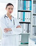 Portrait of confident female doctor standing arms crossed in office