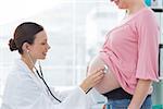 Side view of female doctor examing expectant woman in clinic