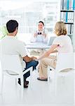 Expectant couple consulting female doctor in clinic