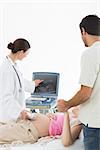 Female doctor showing ultrasound screen to expectant couple in clinic