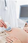 Cropped image of doctor performing ultrasound on pregnant woman in clinic