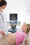 Female doctor using ultrasound on pregnant woman in clinic